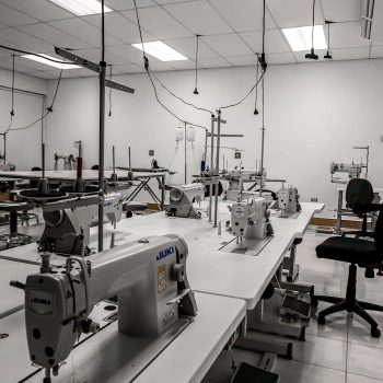 Industrial sewing machines in a well-lit factory room, ready for textile production.